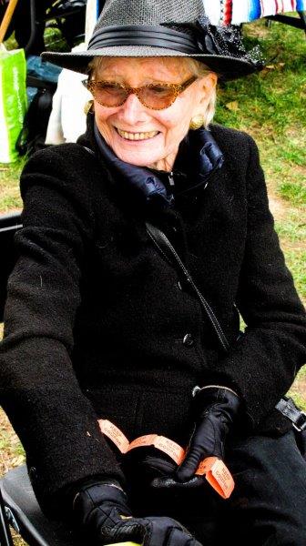 smiling lady in black hat, coat and gloves, with raffle ticket